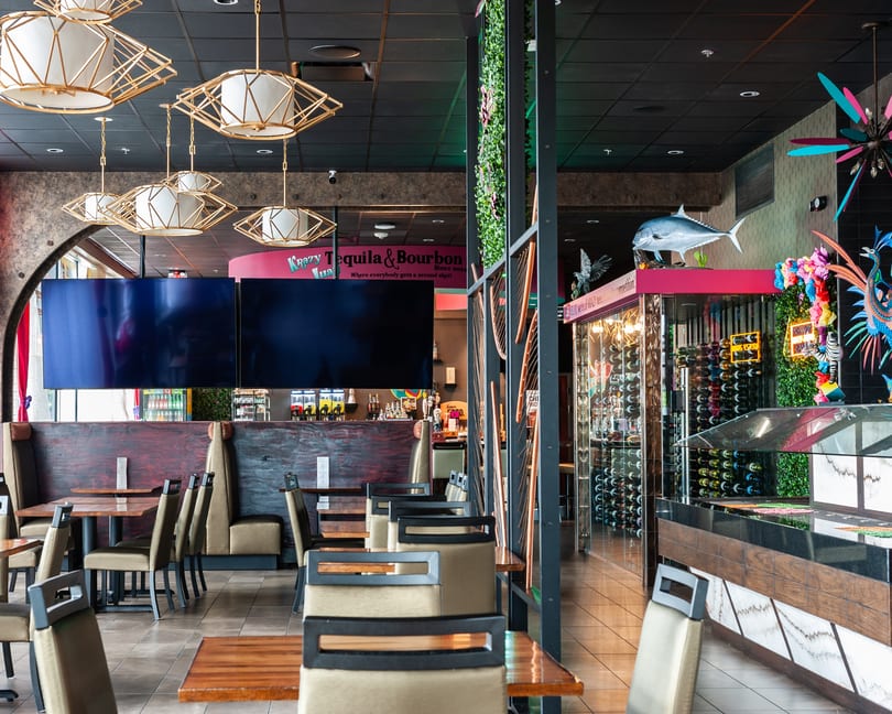 Interior of Krazy Tequila & Bourbon restaurant with tables, booths, decorative lighting, and a wine display.