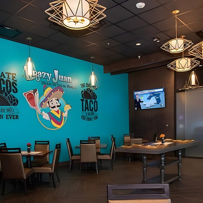 Interior of a Mexican steakhouse with turquoise walls, a cartoon mariachi, and dining tables.